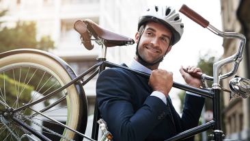 Manlig tjänsteperson i kostym som bär cykeln på axeln.