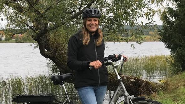 Foto av Henriette Wallén Warner framför en sjö med sin cykel.