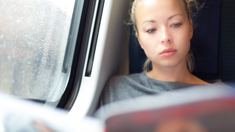Kvinna som läser på ett tåg.