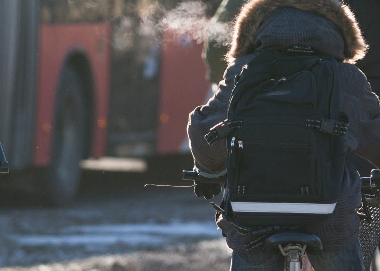 Ungdom på cykel mad buss i bakgrund.