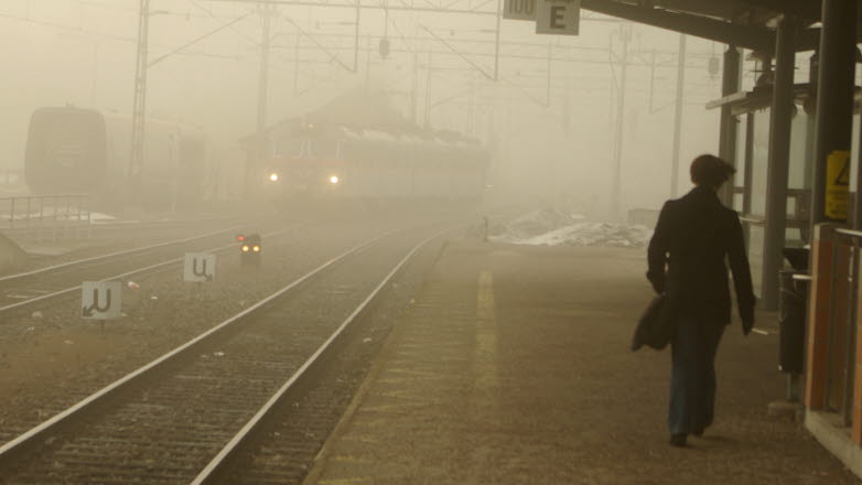 Resenär väntar på tåg i dimma.