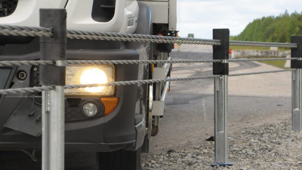 Front end of a lorry next to a wire railing.