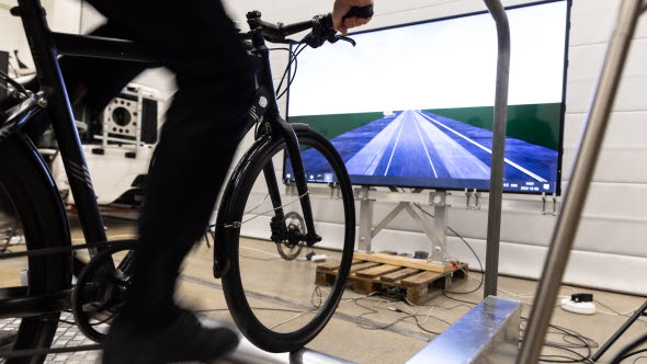 The bicycle and the legs of a person when bicycling on the bicycle simulator while watching virtual surrounding on a screen.