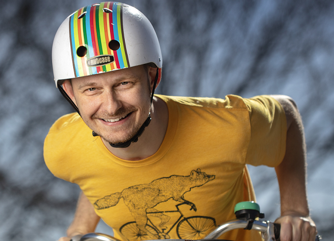 Porträttfoto av en leende Mads Paulsen, DTU, på cykel med färgglad hjälm.