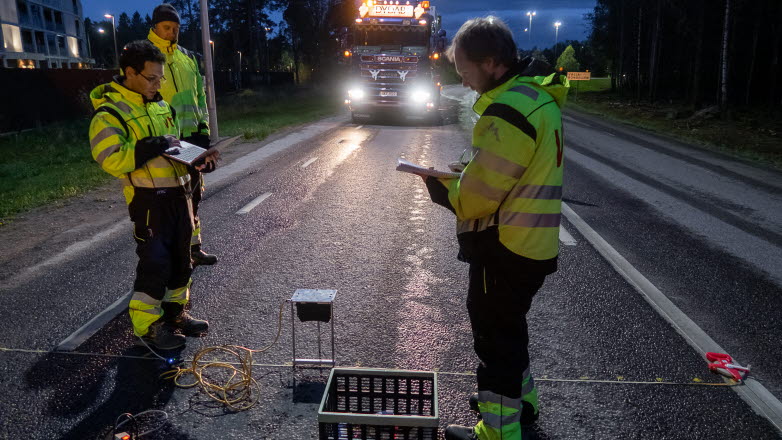 Two men and a lorry at a road in the dark.