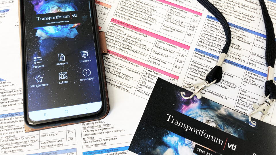 Mobil med Transportforums app öppen som ligger på ett utskrivet programblad.