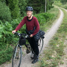 Sonja Forward med cykel på en grusväg i skogen, iförd cykelhjälm.
