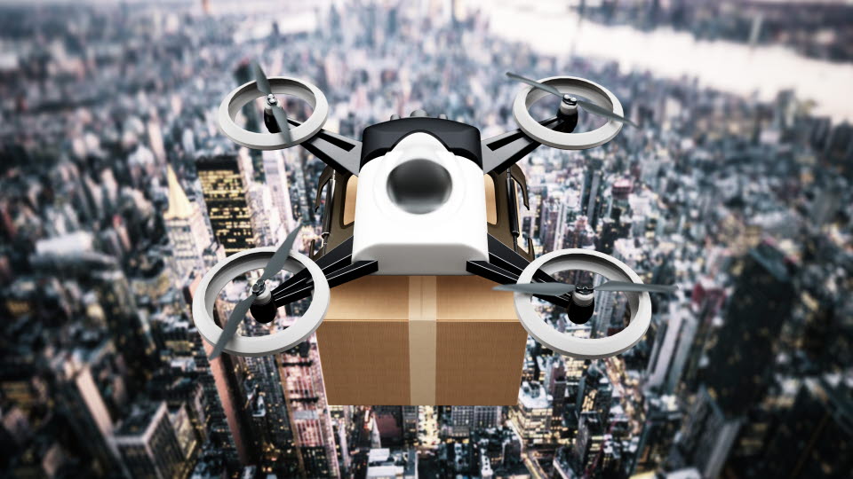 A drone carrying parcels flies over a city.