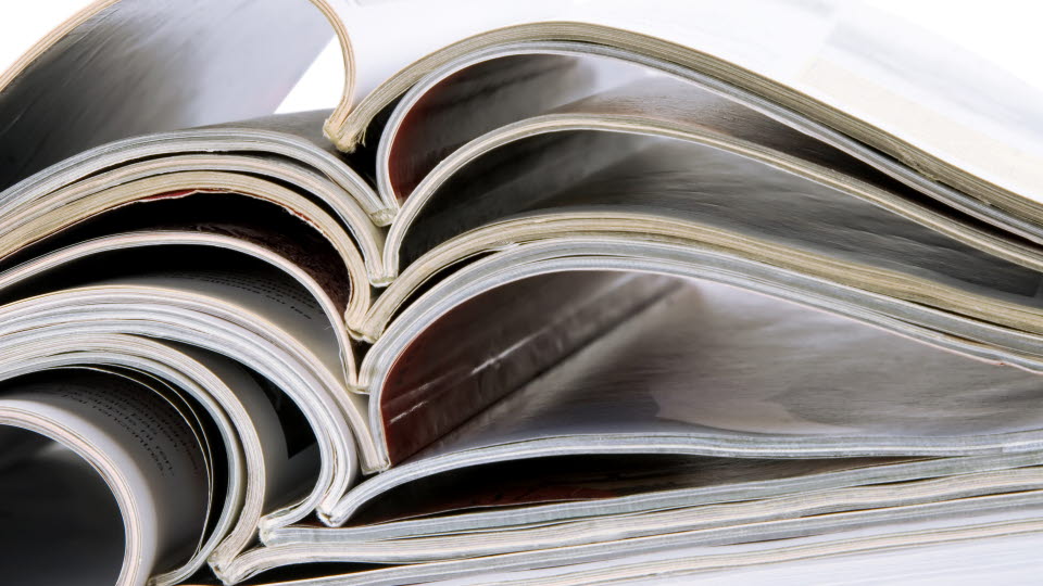 pile of old magazines with bending pages on white background.