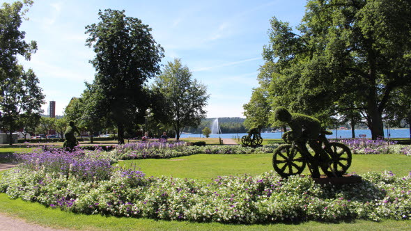 Växtskulpturer föreställande cyklister som cyklar runt en park, vid Vättern, i Motala.