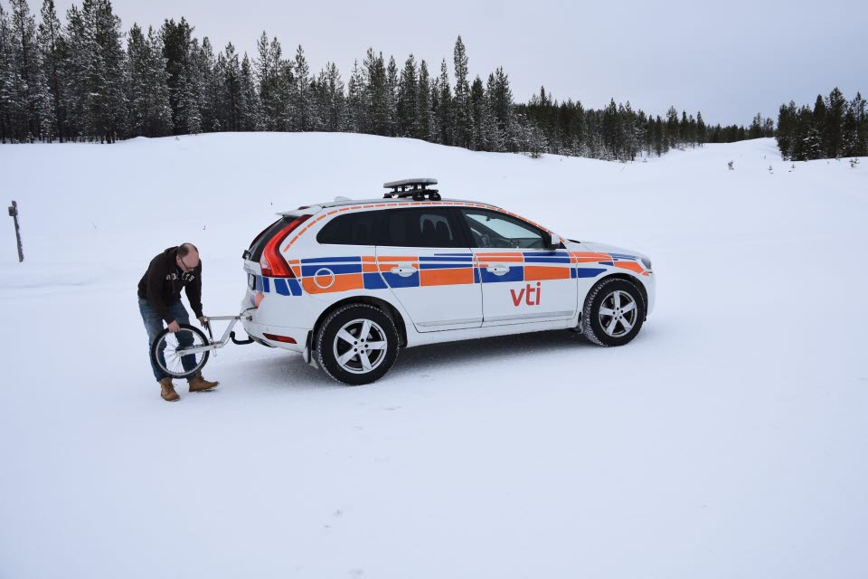 Man outside car in snowy landscape.