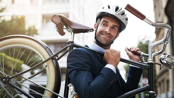 Manlig tjänsteperson i kostym som bär cykeln på axeln.