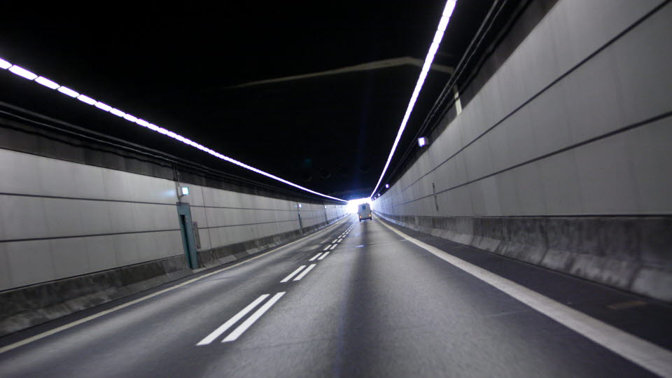Car driving towards light in the end of a tunnel. 