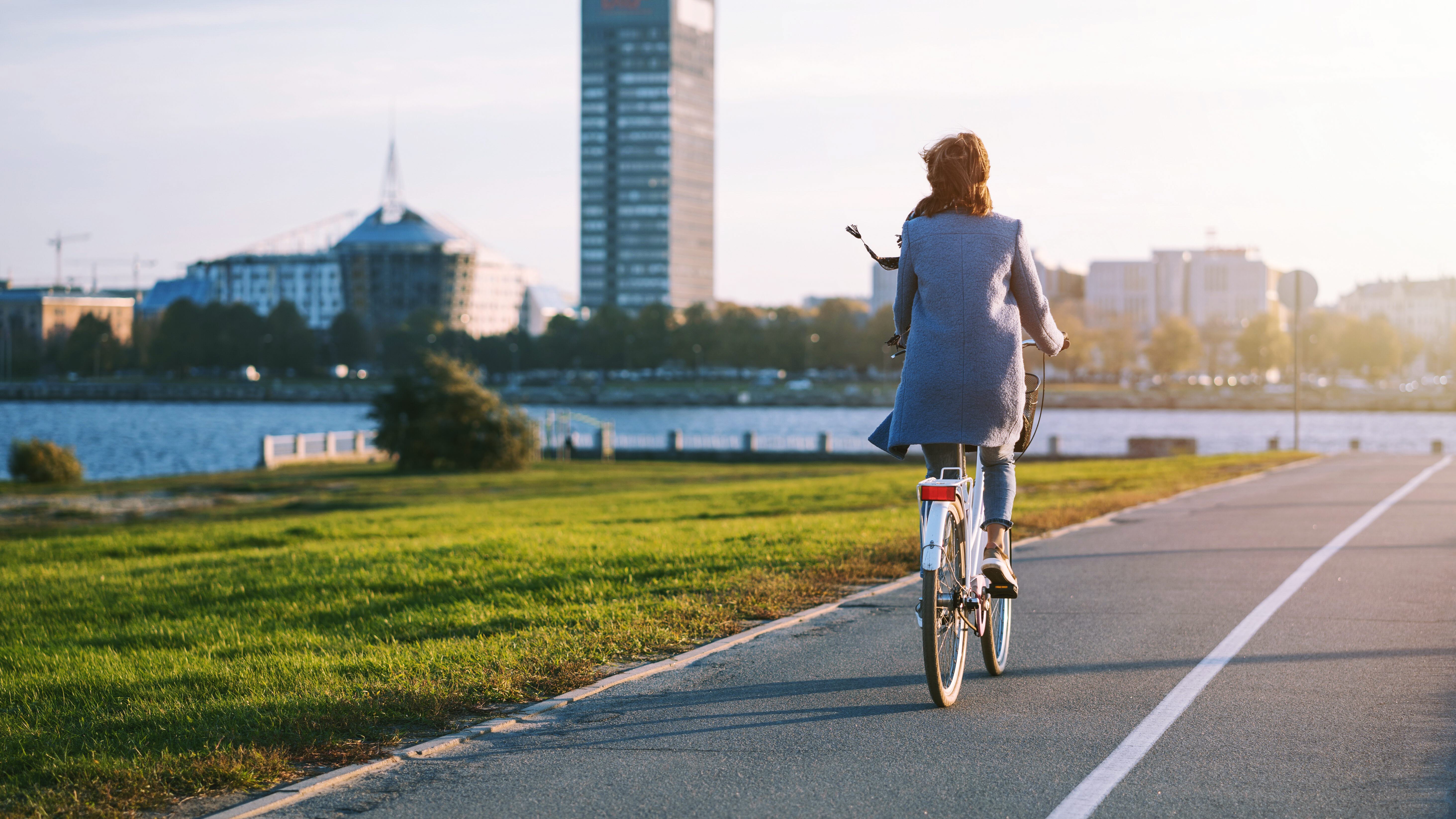 En kvinna som cyklar på en cykelbana i motljus